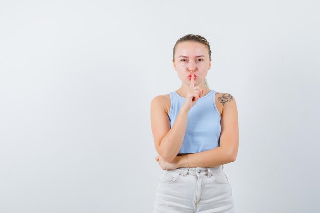 blonde girl is showing gesture of silent on white background