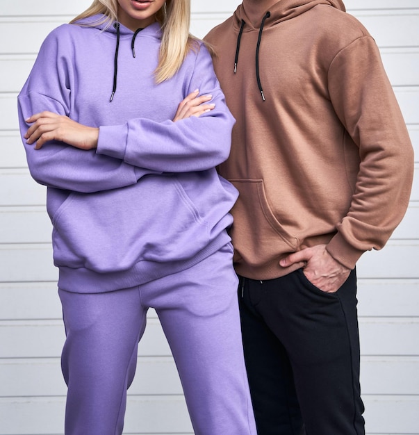 Blonde girl is standing in blue sport outfit Man wears brown hoodie and black pants Couple is wearing street matching outfit