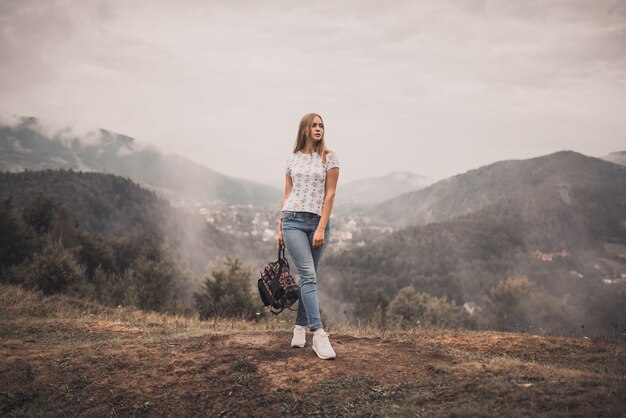 Blonde girl in jeans and shirt on a mountain