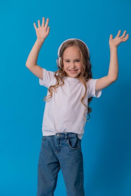 blonde girl in jeans and a white T-shirt listens to music with headphones and dances