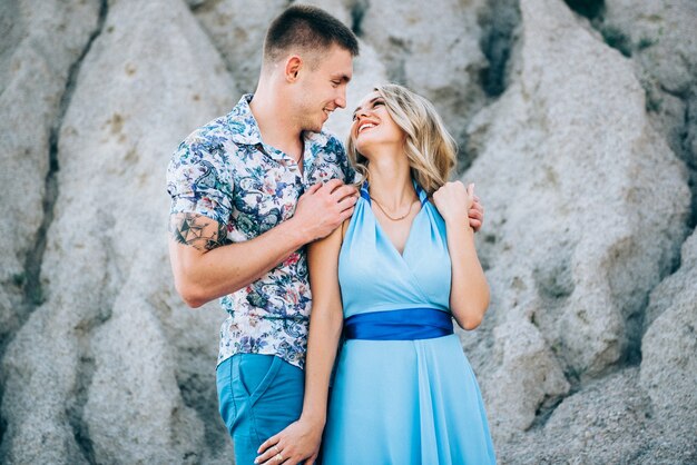 Blonde girl in a light blue dress and a guy in a light shorts and short shirt in a granite quarry