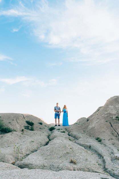 Blonde girl in a light blue dress and a guy in a light shorts and short shirt in a granite quarry