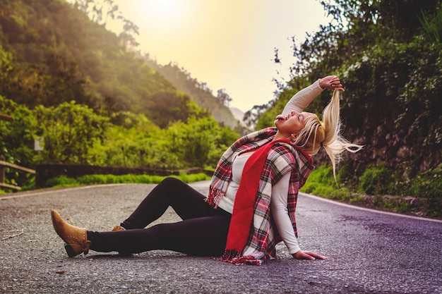 Photo blonde girl, living crazy, sitting in the middle of the road with her tongue out.