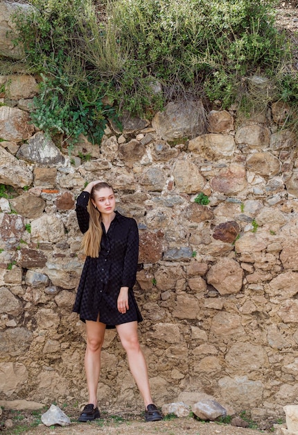 The blonde girl look at the left in black dress on stone background