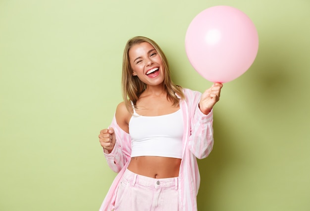 Blonde girl in a pink outfit posing