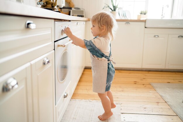 ブロンドの女の子は、キッチンのガスのオーブンで休日のペストリー ケーキ デザートを準備します。