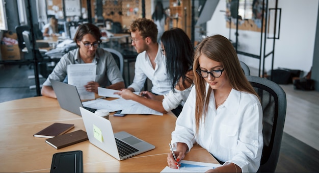 Blonde girl reads document. Young business people in formal clothes working in the office.