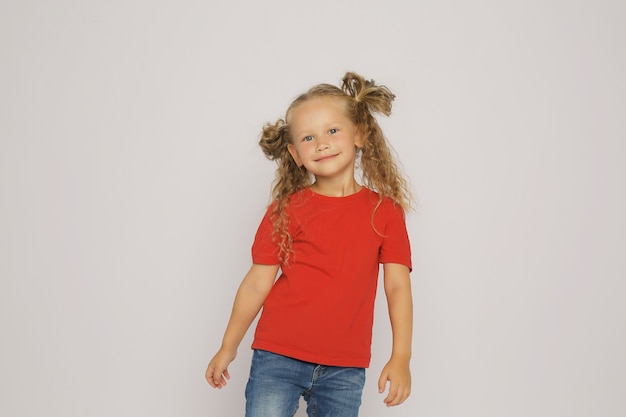 a blonde girl in a red Tshirt and jeans with ponytails shows emotions