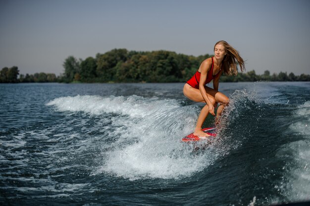 Ragazza bionda che guida sul wakeboard rosso