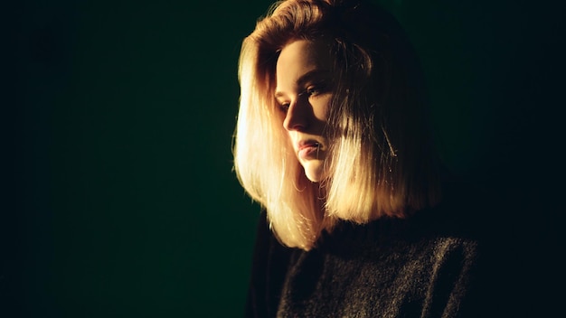 Blonde girl in a room near the wall in the rays of light