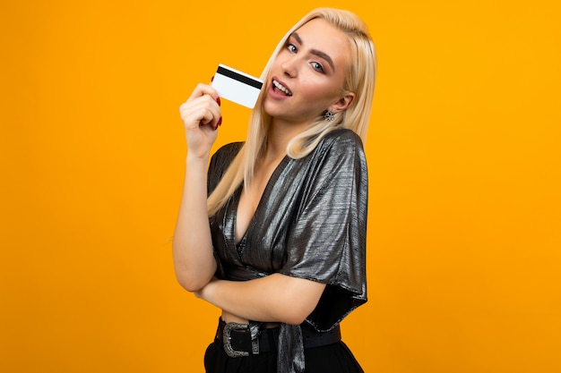 blonde girl in a shiny blouse holds a credit card