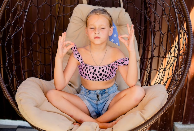 Photo a blonde girl in shorts and a top meditates in a street chair