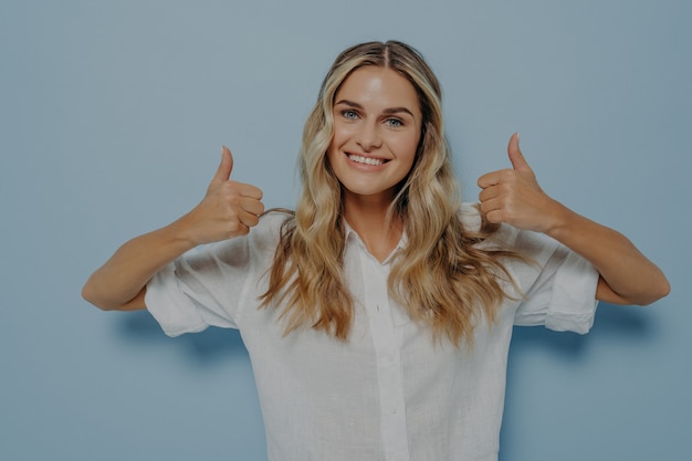 Blonde girl showing thumbs up gesture with both hands