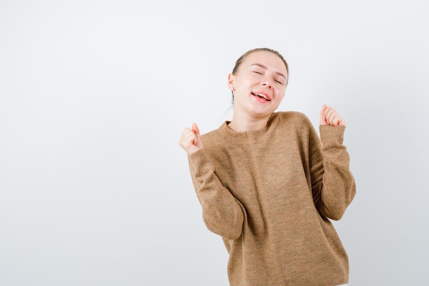 ブロンドの女の子は白い背景に栄光のジェスチャーを示しています