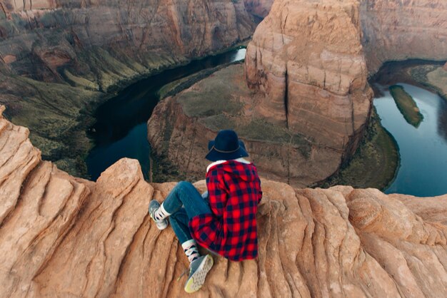 Blonde girl sitting Horseshoe Bend in Glen Canyon National Recreation Area in early dawn