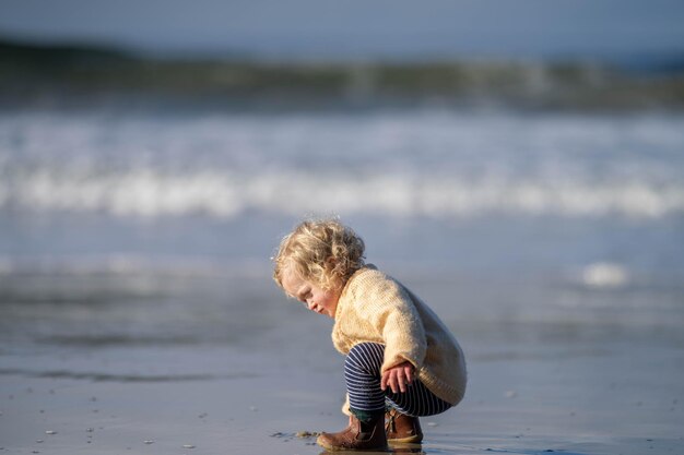 blonde girl toddler exploring on the sand on the beach in australia