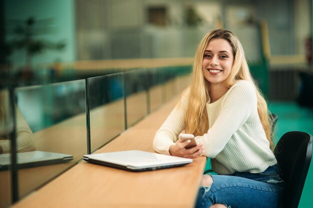 Photo blonde girl use phone in library