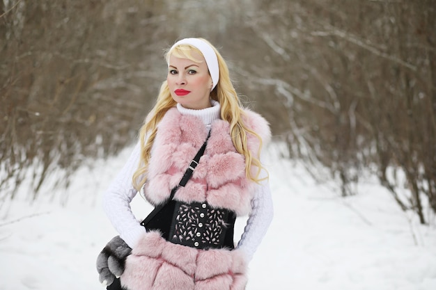 Blonde girl on a walk in a winter park with a cloudy day