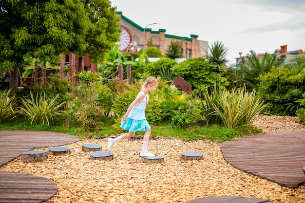 Blonde girl in white and blue dress playing on the playground