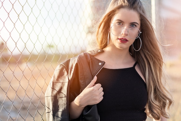 Photo blonde girl with glasses in trendy posed at sunset