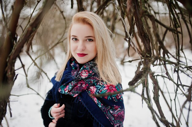 Blonde girl with hand embroidered scarf posed at winter day.