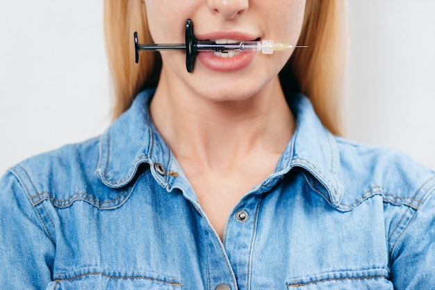 Blonde girl with a syringe in her teeth