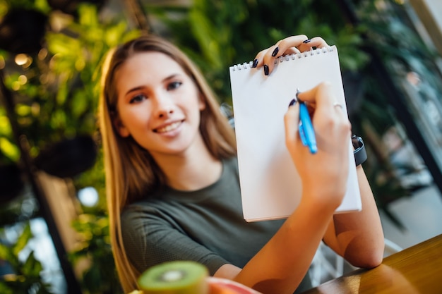 Blonde girl working with  writing diet plan on notepad