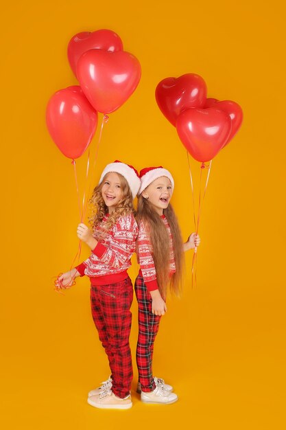 blonde girls in a christmas jumper in plaid trousers santa claus hats balloons