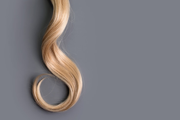 Blonde hair curl isolated on grey background