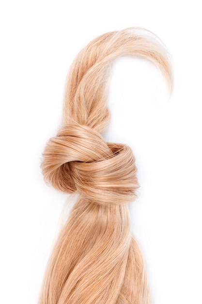 Blonde hair lock tied in knot. Strand of honey blonde hair isolated on white background, top view. Hairdresser service, hair strength, haircut, dying or coloring, hair extension, treatment concept.