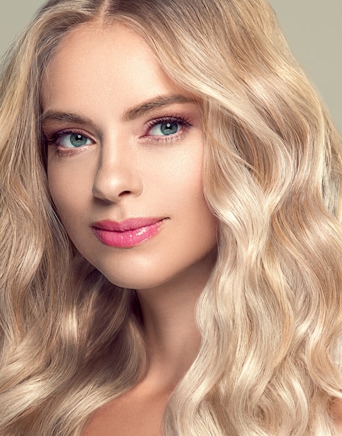 Blonde Hair Woman Beautiful Curly Hairstyle Wavy Long hair. Natural make up. Studio shot. On gray.