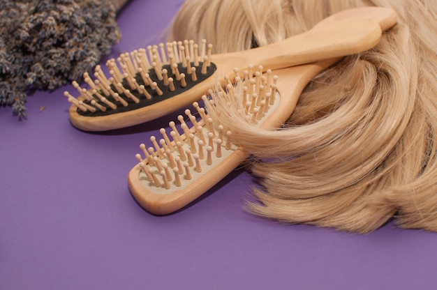 Blonde hair wooden combs and a bouquet of dried lavender on a purple background