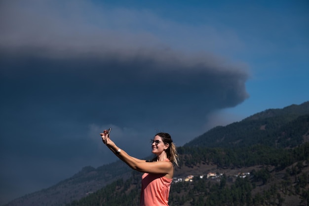 Blonde-haired woman taking a selfie with storm clouds