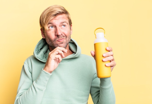 Uomo adulto bello biondo che tiene un thermos di caffè