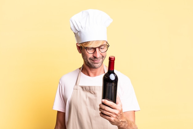 Blonde handsome chef  adult man holding a bottle of wine