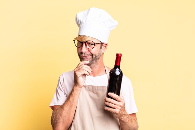 Blonde handsome chef adult man holding a bottle of wine