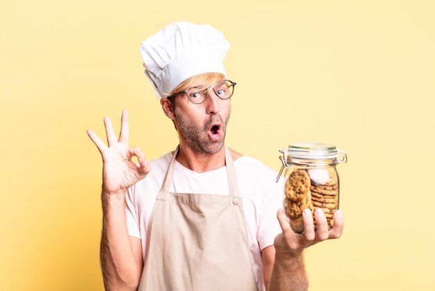 Blonde handsome chef  adult man holding a homemade cookies bottle