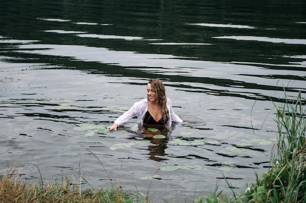 Blonde happy beautiful woman swimming in the river among the waves.