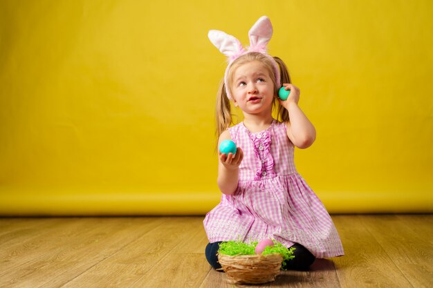 Blonde happy girl with bunny ears and basket of eggs for Easter