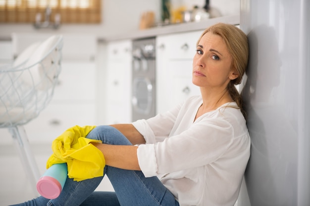 Blonde housewife in protective gloves feeling tired