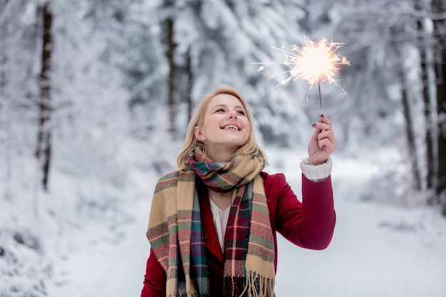 Blonde in een rode jas met sterretje in een besneeuwd bos