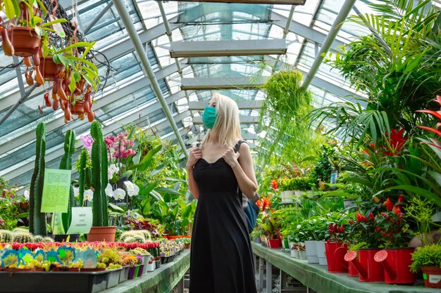 Blonde in gezichtsmasker in palmkas van de botanische tuin