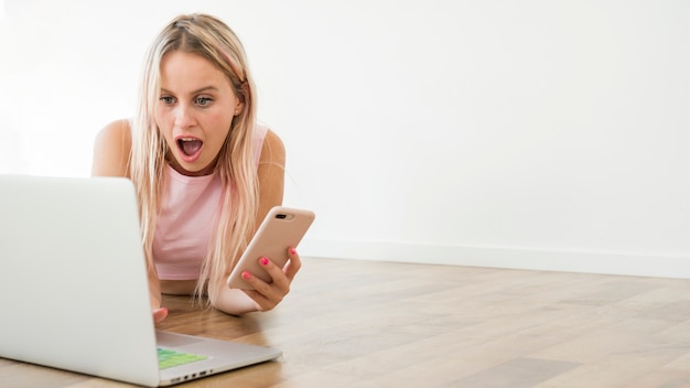 Foto blonde influencer met behulp van laptop op de vloer