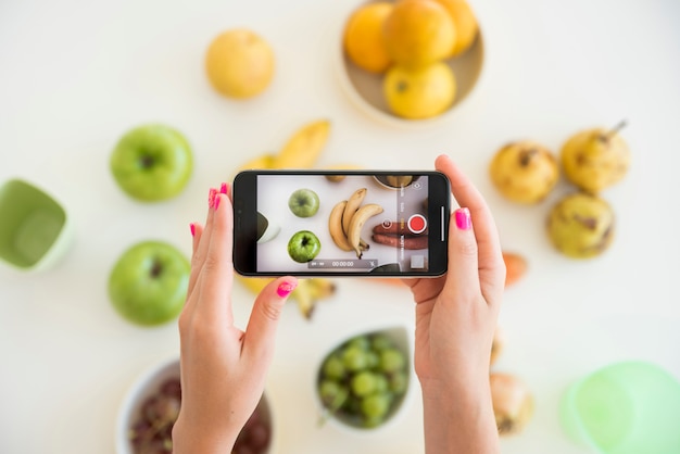 Photo blonde influencer taking picture of fruit