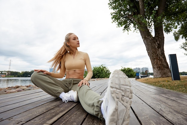 Foto blonde jonge atletische vrouw die aan het trainen is in een park in een stedelijke omgeving aantrekkelijke atletische vrouw die 's ochtends buiten traint kopieerruimte gezondheid fitness concept