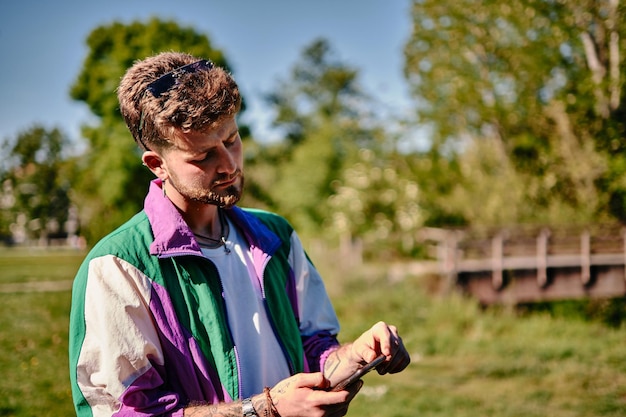 Blonde jonge jongen die met een verbaasd gezicht naar het scherm van zijn mobiele telefoon kijkt