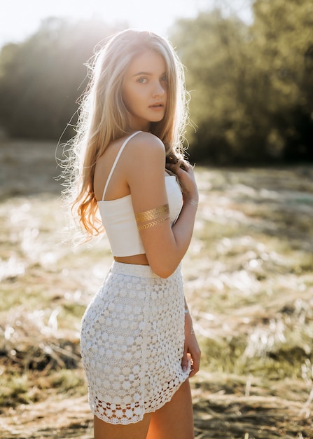 Blonde jonge vrouw, gekleed in een witte gehaakte jurk