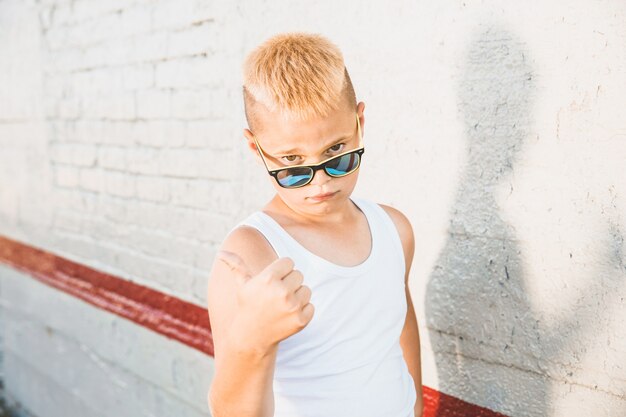 Foto blonde jongen in een wit t-shirt met zonnebril op zijn hoofd. close-up portret