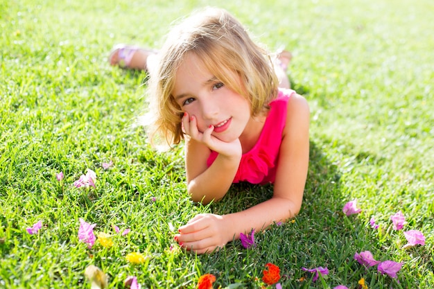 Blonde jongen meisje liggend ontspannen in de tuin gras met bloemen