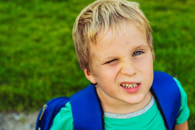 Blonde jongen met sproeten blauwe rugzak gezicht scheel wil niet naar school of kleuterschool artistieke emoties gezichtsuitdrukking familierelatie micromomenten van jeugdeducatie